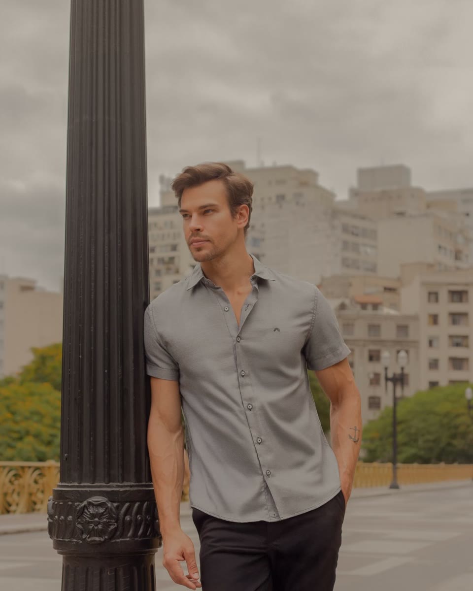 Homem de camisa cinza de manga curta em look urbano